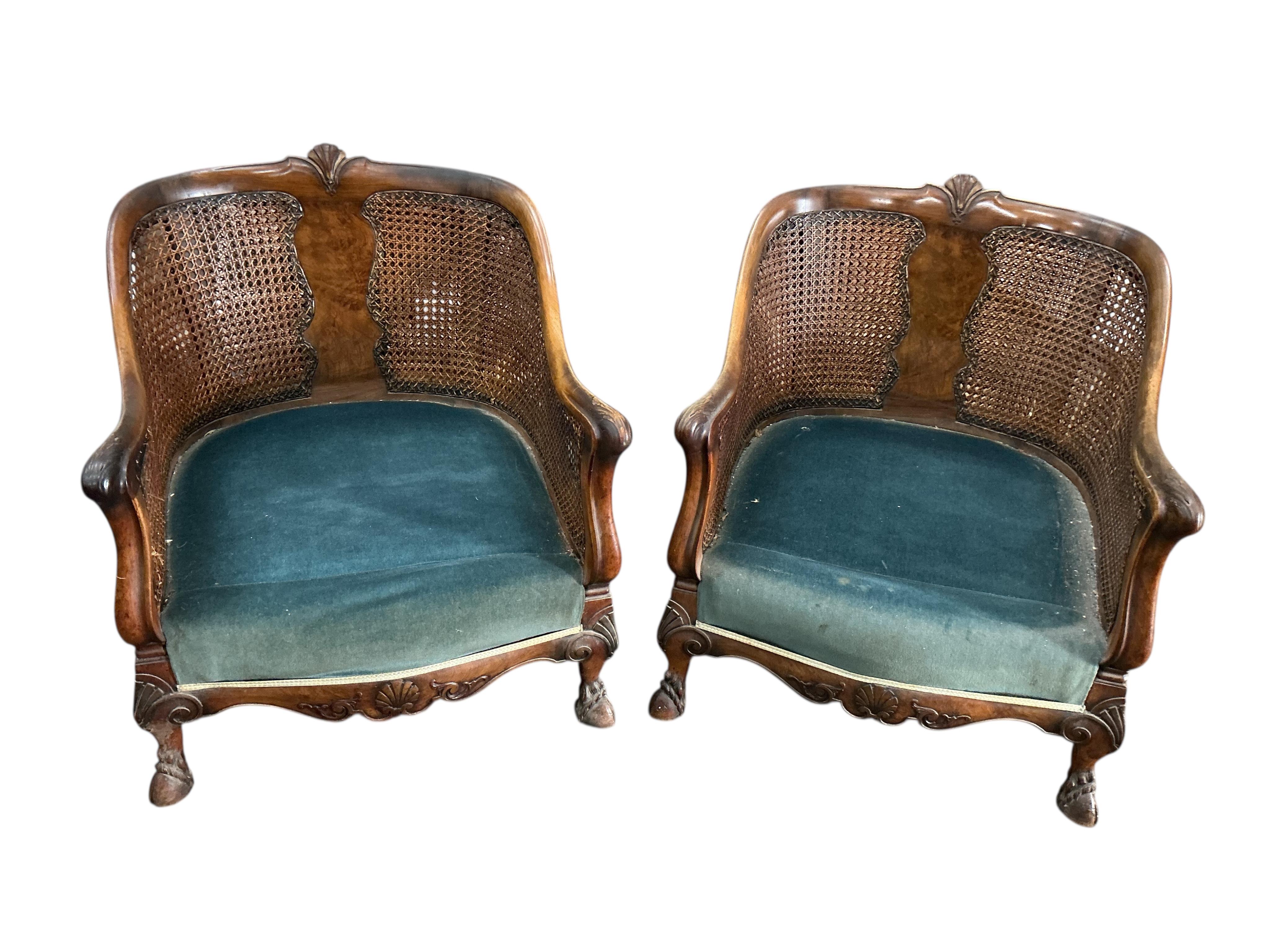 An early 20th century carved walnut and double canework three piece bergère suite, cane in need of repair